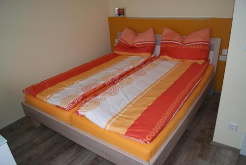 - un lit avec des draps orange et orange et des oreillers rouges dans l'établissement Privatzimmer Mitterbacher, à Fohnsdorf