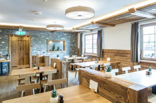 a restaurant with wooden tables and chairs and a brick wall at Hotel Reuti in Hasliberg