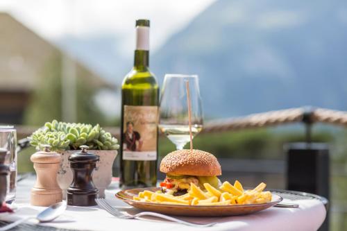 a sandwich and french fries on a table with a bottle of wine at Hotel Reuti in Hasliberg