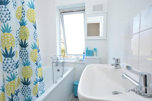 a bathroom with a sink and a pineapple shower curtain at London Deluxe Four Bedroom House in Dagenham