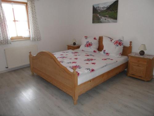 ein Schlafzimmer mit einem Holzbett mit Blumen darauf in der Unterkunft Ferienwohnung Engelhardt in Oberreute