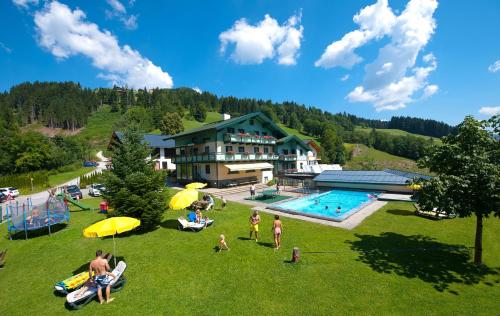 a group of people sitting in the grass near a resort at Appartements Tannenhof in Wagrain