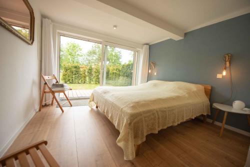 a bedroom with a bed and a large window at kleineHauszeit das Ferienhaus am Grimnitzsee in Joachimsthal