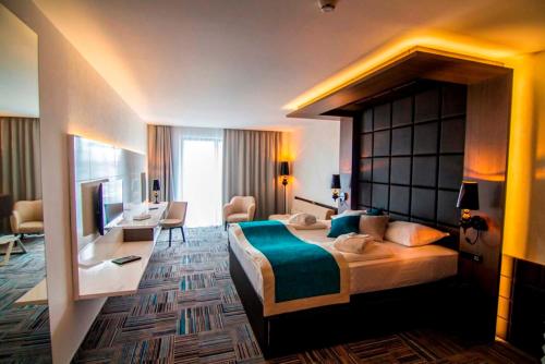 a hotel room with a large bed and a desk at Hotel Hills Sarajevo Congress & Thermal Spa Resort in Sarajevo
