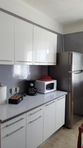 une cuisine avec des armoires blanches et un réfrigérateur en acier inoxydable dans l'établissement Appartement avec terrasse quartier Montplaisir, à Arles