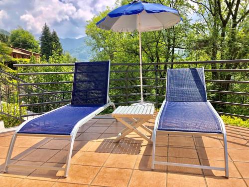 two blue chairs and an umbrella on a patio at Residenza Ai Ronchi 1 2 6 in Maccagno con Pino e Veddasca