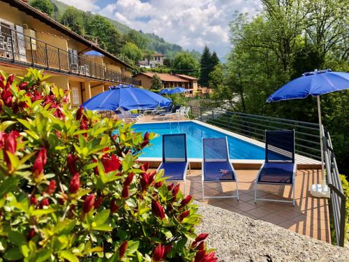 a pool at a hotel with two chairs and umbrellas at Residenza Ai Ronchi 1 2 6 in Maccagno con Pino e Veddasca