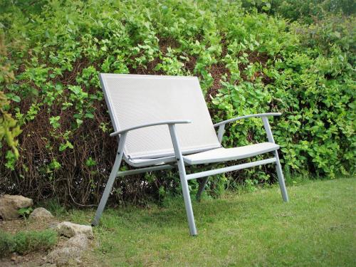 a white chair sitting in the grass at Nefelejcs Apartmanház in Gyenesdiás