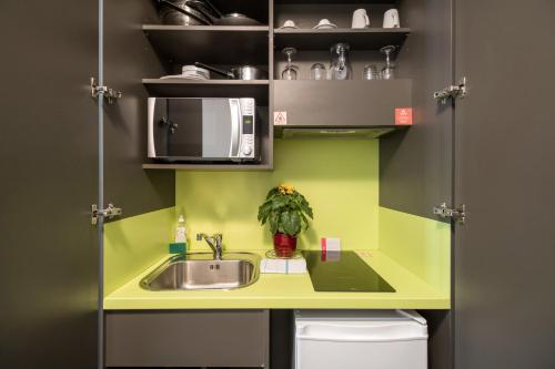 
a kitchen with a sink and a microwave at Appart’City Confort Le Bourget - Aéroport in Le Bourget
