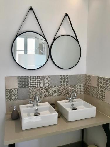 a bathroom with two sinks and two mirrors at Ô 36 Rempart Sud B&B in Aigues-Mortes