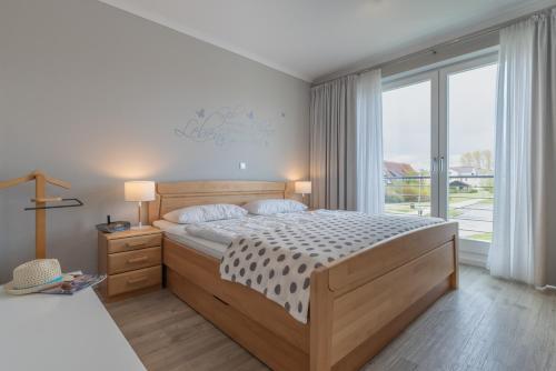 a bedroom with a bed and a large window at Villa Sanddorn - Ferienwohnungen in Börgerende-Rethwisch