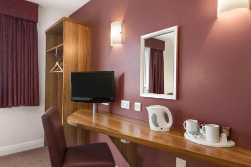 a room with a desk with a tv and a mirror at Days Inn Corley NEC - M6 in Coventry