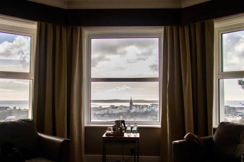 a room with three windows with a view of a city at The Park Hotel in Tenby