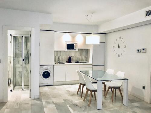 cocina y comedor con mesa de cristal y sillas en Domus Apartamentos Granada con parking gratuito en pleno centro en Granada