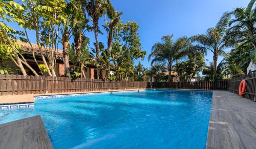 a swimming pool with blue water and palm trees at Hacienda Roche Viejo in Conil de la Frontera