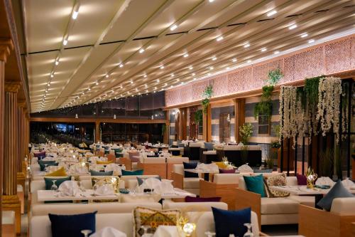 uma sala de jantar com mesas e cadeiras brancas em The Palms Beach Hotel & Spa em Kuwait