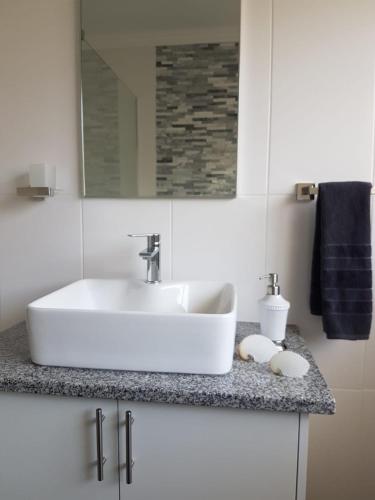 Un baño con un lavabo blanco y un espejo. en Aloe @ the Sea, en Mossel Bay
