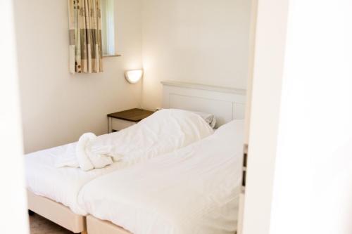 een slaapkamer met 2 bedden en witte lakens bij Bungalowpark Hoge Hexel in Hoge-Hexel