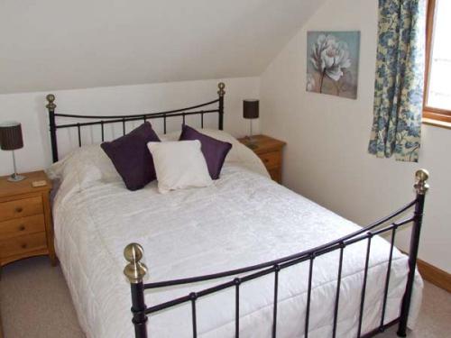 um quarto com uma cama grande com almofadas roxas e brancas em Rhiastyn Barn em Hyssington