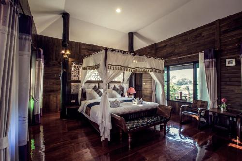 1 dormitorio con cama con dosel y mesa en Buraphat Resort, en Chiang Dao