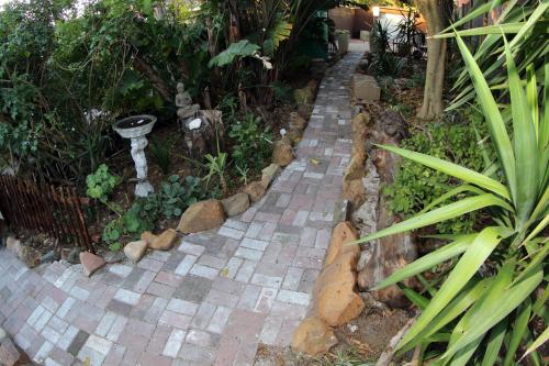 a brick walkway in a garden with plants at The Buddha Garden in Cape Town