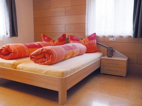 uma cama com almofadas vermelhas e laranja em Apartment Silbertal - Ferienwohnung em Silbertal