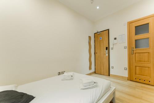 a white room with two beds and a wooden door at New Kent Apartments in London