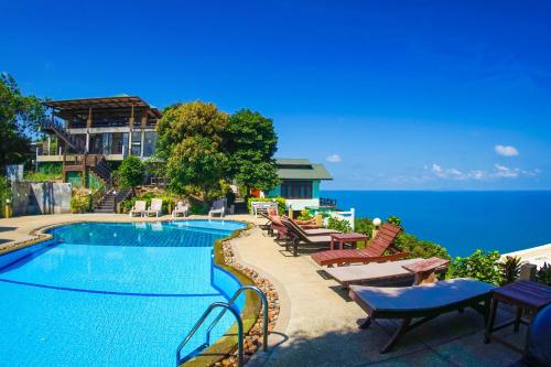 a swimming pool with tables and chairs next to the ocean at Phangan Utopia Resort in Mae Haad
