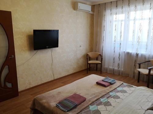 a bedroom with a bed and a tv on the wall at Квартира в центре Саранска in Saransk