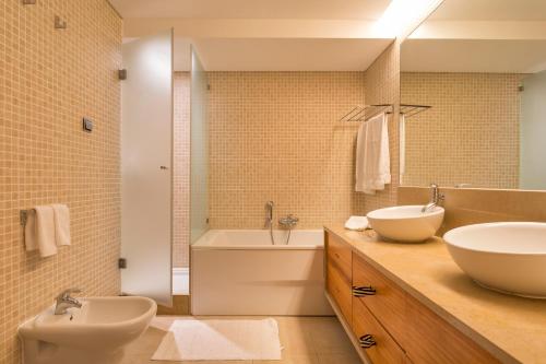 ein Badezimmer mit zwei Waschbecken, einer Badewanne und einem WC in der Unterkunft Alexandra in Vale do Lobo