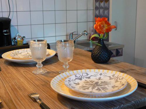a wooden table with two plates and glasses on it at Les Tulipiers, Parking Sécurisé, Lit Queen-Size, le Mans Centre in Le Mans