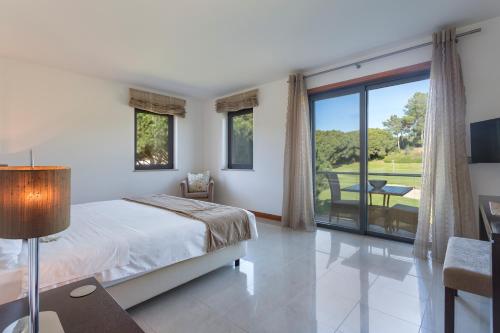 sypialnia z łóżkiem i przesuwnymi szklanymi drzwiami w obiekcie Alexandra w mieście Vale do Lobo