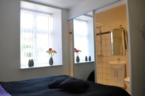 a bedroom with a bed and a sink and two windows at AB Centrum Aarhus Bed without Breakfast in Aarhus
