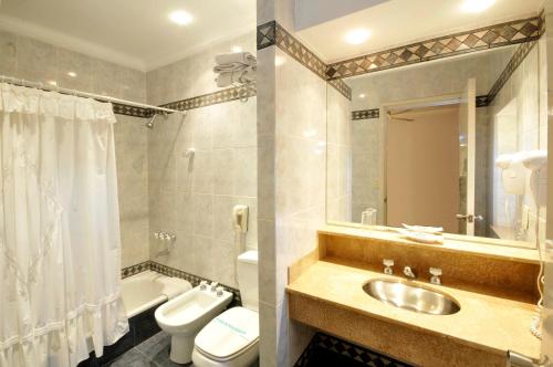 a bathroom with a sink and a toilet and a tub at Hotel Muñiz in Bahía Blanca