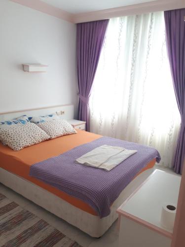 a bedroom with a bed with purple curtains at Aygun Apart Daire in Mahmutlar