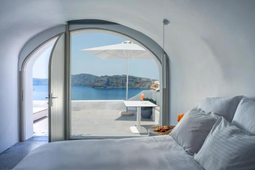 a bedroom with a bed and a table with an umbrella at Echoes Luxury Suites in Oia