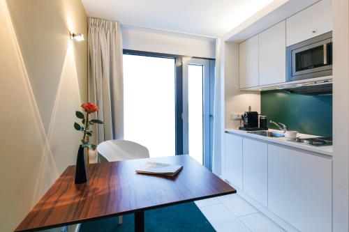 a kitchen with a wooden table with a vase of flowers at Pandion Boardinghouse in Munich