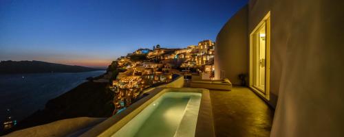 a building with a swimming pool with a view of the ocean at Echoes Luxury Suites in Oia