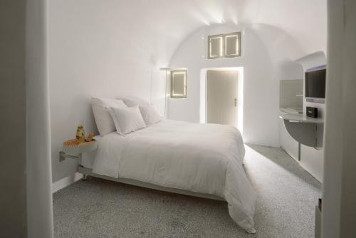 a white bedroom with a white bed and a kitchen at Echoes Luxury Suites in Oia