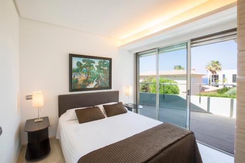 a bedroom with a bed and a large window at Villa Agusmar in Cala Blava