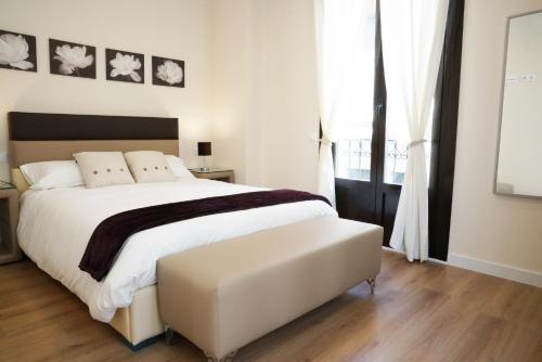 a bedroom with a large white bed and a window at APARTAMENTOS RELOJ DE BERGERÓN in Logroño