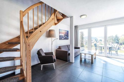 Sala de estar con escalera, silla y mesa en Panoramahaus _100_ im Feriendorf a en Truppach