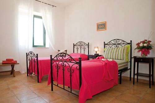 a bedroom with three beds with pink sheets and a table at Tenuta Badessa in Casalabate