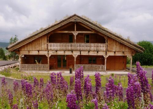 a wooden house with purple flowers in front of it at Ker Carlit in Saint-Pierre-dels-Forcats