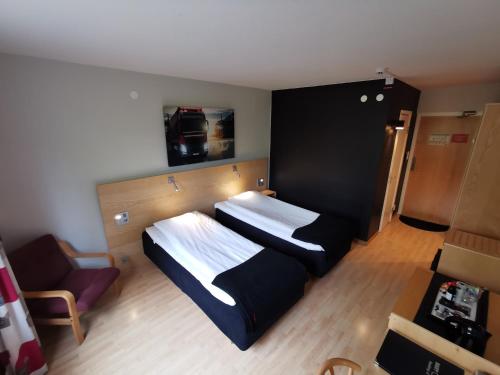 una habitación de hotel con 2 camas y una silla en RastPunkt Laxå, en Laxå