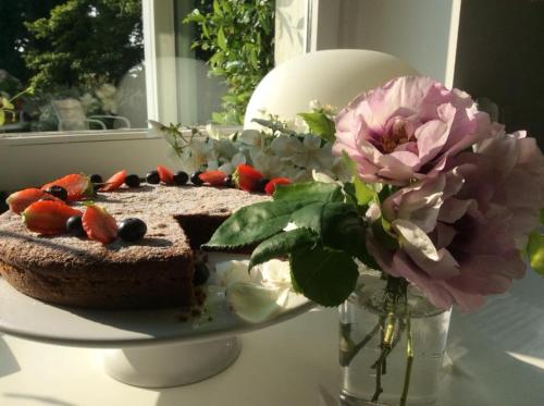 a cake on a plate on a table with a vase of flowers at Villa La Maggiorana in Rivoli
