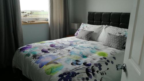 a bed with a colorful comforter and a window at The Fisherman's Snug self catering North Uist in Paible