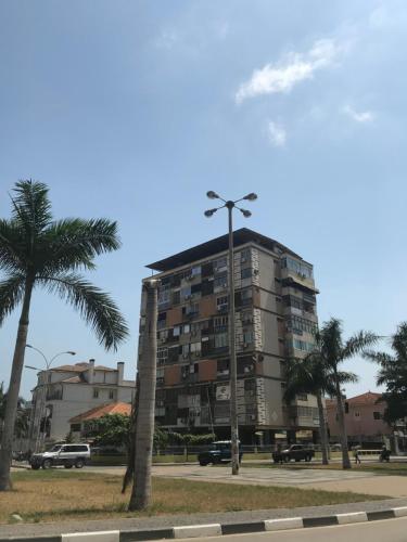 a tall building with a palm tree and a street light at Rua José de Oliveira Barbosa in Luanda