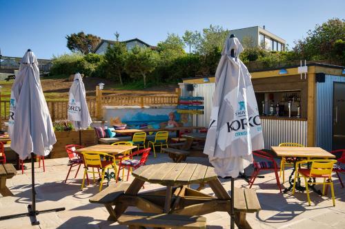 a patio with tables and chairs and umbrellas at Oystercatcher Apartments in Polzeath
