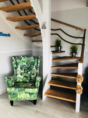 a living room with a green chair and stairs at Nadmorski Zaułek in Jastrzębia Góra